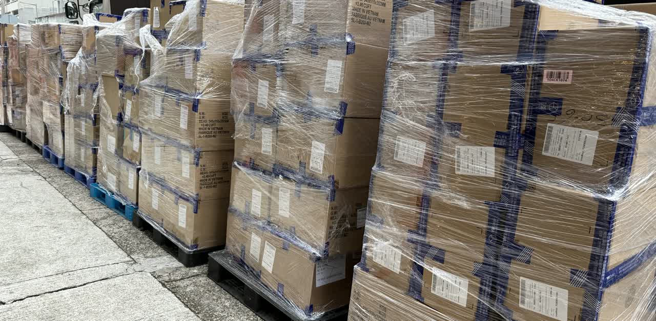 Shrink-wrapped pallets of sealed export cartons lined up on a Hong Kong kerb, staged for collection.